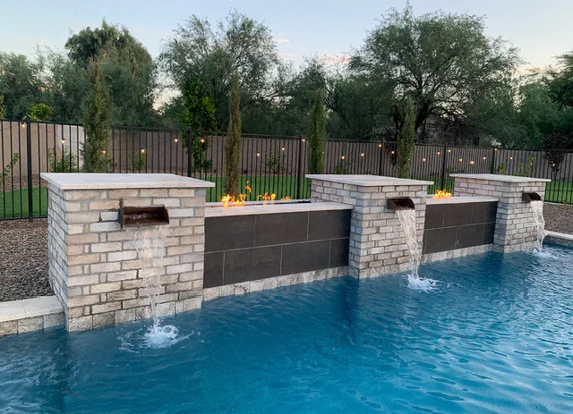 Stone and tile water feature wall with fire troughs above a pool